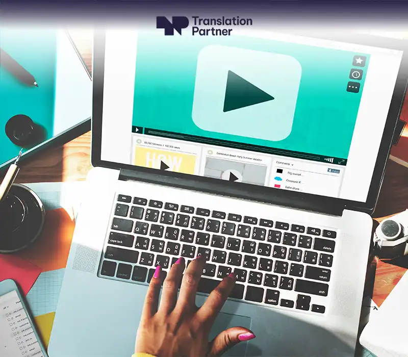 Hand on laptop with video play button and Translation Partner logo for media services
