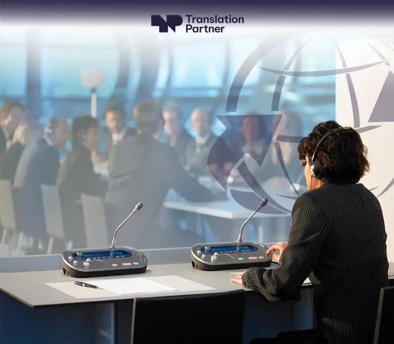 Interpreter at conference with Translation Partner logo and interpretation equipment