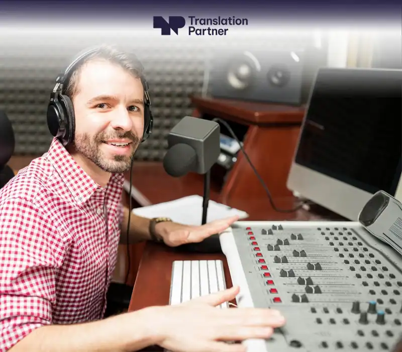 Voice-over artist at studio microphone and mixing desk with Translation Partner.